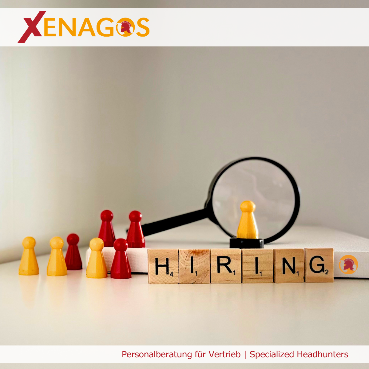 Mehrere Spielfiguren in Rot und Gelb stehen neben einer Lupe und Buchstabensteinen mit dem Wort „Hiring“. Das Bild veranschaulicht die parallele Suche nach passenden Vertriebspersönlichkeiten und die strategische Herausforderung, mehrere Positionen gleichzeitig gezielt zu besetzen.